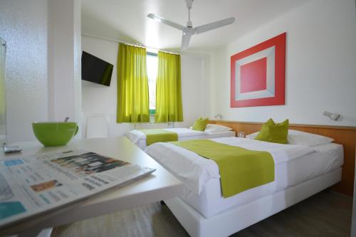 a bedroom with two beds and a table with a magazine at Motel Hirschberg in Hirschberg