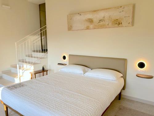 a bedroom with a bed with white sheets and a staircase at The Lake Suites com - Luxury stay in Lazise in Lazise