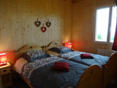 2 Betten in einem Zimmer mit Herzen an der Wand in der Unterkunft Chalet Chez Picou in La Tour-dʼAuvergne