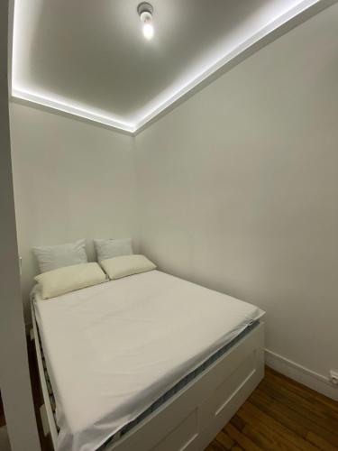 - un petit lit dans une chambre dotée d'un mur blanc dans l'établissement Tour Eiffel Alasseur 2 Paris, à Paris