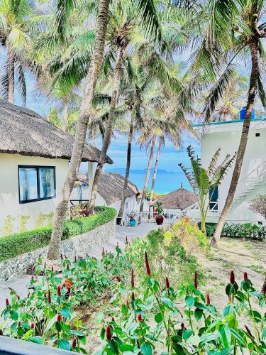 a house with palm trees and a garden with flowers at Paradise Resort Doc Let - All Inclusive in Doc Let
