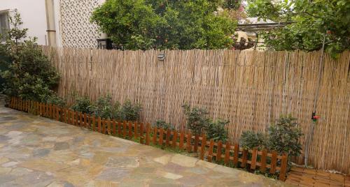 a wooden fence with plants on top of it at Aphrodite Apartment Near The Beach and The Airport in Áyios Spirídhon