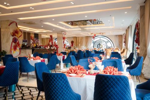 a banquet hall with tables and blue chairs at Sandals Vista Hotel in Bao Loc
