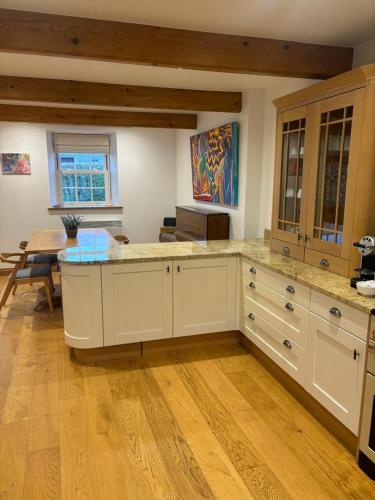 a large kitchen with white cabinets and wooden floors at Two Trees, By Birch Stays in Hetton
