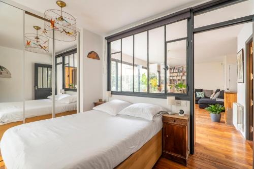 une chambre avec un grand lit blanc et de grandes fenêtres dans l'établissement Veeve - Wooden Warmth, à Paris