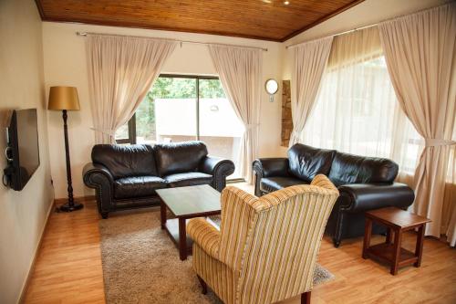 a living room with leather furniture and a table at Blyde Canyon, A Forever Resort in Matibidi