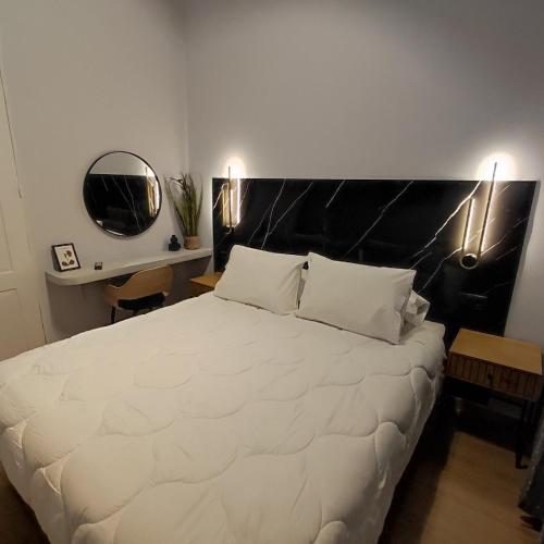 a bedroom with a large white bed with a black headboard at Byzantium Suite in the centre of Hermoupolis in Ermoupoli
