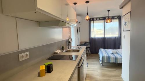une cuisine avec un évier et un canapé dans une chambre dans l'établissement 091-Les Cyprianes - 2 pers - Parking - Piscine, à La Grande Motte