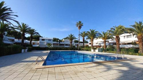 une grande piscine avec des palmiers et des bâtiments dans l'établissement 091-Les Cyprianes - 2 pers - Parking - Piscine, à La Grande Motte