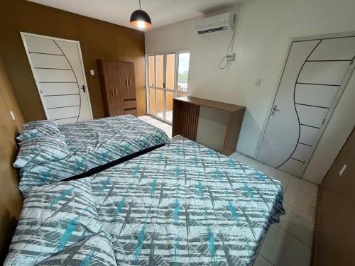 a bedroom with a bed with a blue and white comforter at Hotel e Restaurante Casa Paraense Original, px ao aeroporto in Manaus