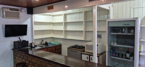 a kitchen with a counter with a microwave and a refrigerator at Pousada Vino & Leta O seu parador no centro in Grão Pará