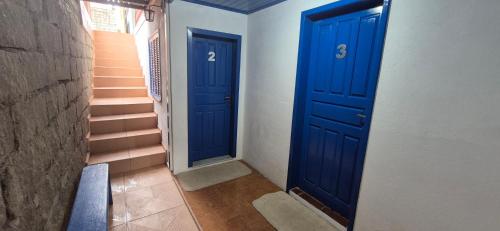 two blue doors in a hallway with stairs at Pousada Vino & Leta O seu parador no centro in Grão Pará