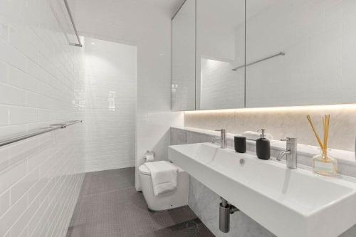 a white bathroom with a sink and a toilet at Urban Retreat Near Sydney Harbour in Sydney