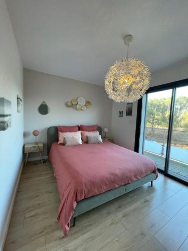 une chambre avec un grand lit et un lustre dans l'établissement A HOSSEGOR, Jolie maison avec SPA pour sejour bien être, à Soorts-Hossegor