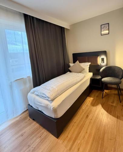 a bedroom with a bed and a chair and a window at Gasthaus Adler in Dietingen