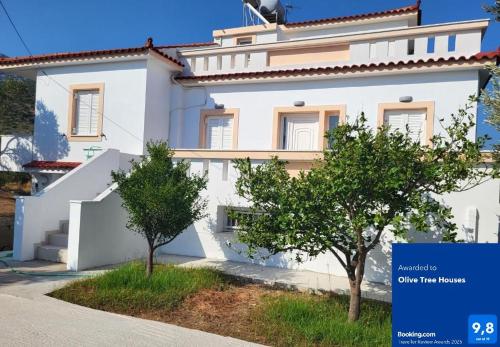 a white house with two trees in front of it at Olive Τree Ηouses in Votsalákia
