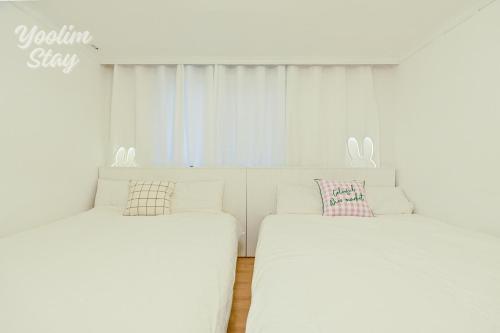 two beds in a room with white walls at Yoolim stay # 건대입구# 성수# 잠실롯데타워 in Seoul