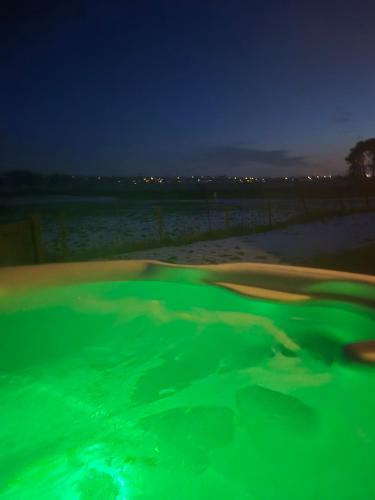 a pool of green water in a golf course at night at Bowland Breaks-A Luxury Barn Conversion with Optional Hot Tub, Log burner and countryside views in Longridge