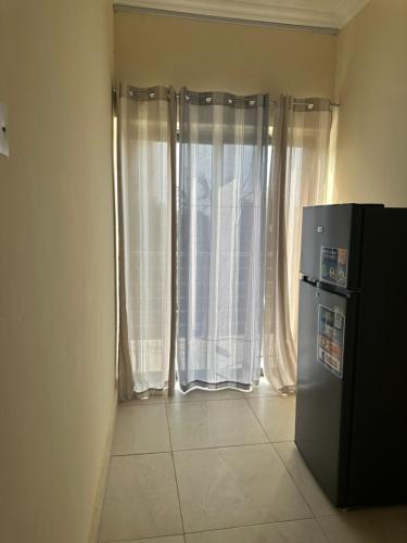a room with a refrigerator and a window with curtains at AMS Global in Accra