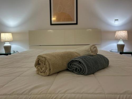 a bed with two towels on it with two lamps at ConVistaApartment with Pool in Portimão