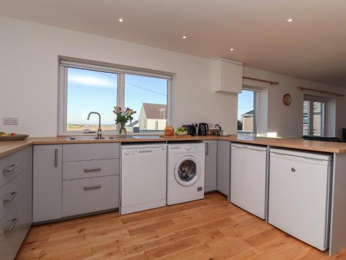 a kitchen with white cabinets and a washer and dryer at Bayview in Bragor