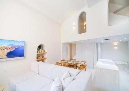a white living room with a white couch and a tv at Santorini by The Heim in Manchester