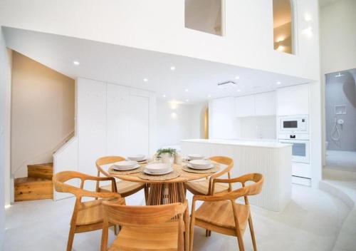 a white kitchen with a wooden table and chairs at Santorini by The Heim in Manchester