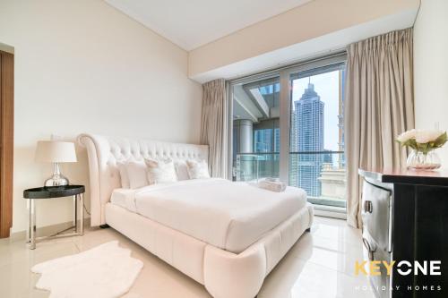 a white bedroom with a large bed and a large window at Captivating Sky & Sea Views in Two Bedroom Suite in Dubai