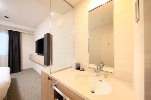 a bathroom with a sink and a large mirror at Richmond Hotel Yokohama Ekimae in Yokohama