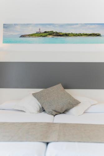 a bed with two pillows and an island in the ocean at Hotel Amic Miraflores in Can Pastilla