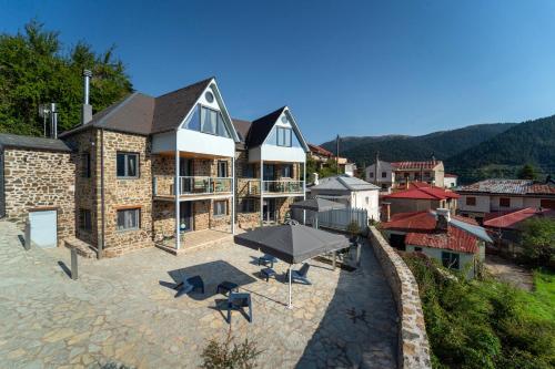 een huis met een parasol en stoelen op een patio bij Dandy Villas Karpenisi Complex - Lux Chalets - Inflatable Pool-Hot Tub in Áyios Nikólaos