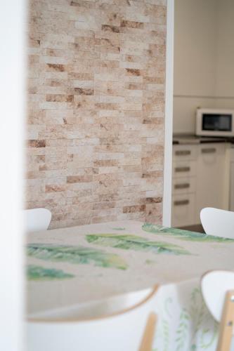 a table with white chairs and a brick wall at APARTAMENTO SAN MIGUEL N.2 in Jarandilla de la Vera