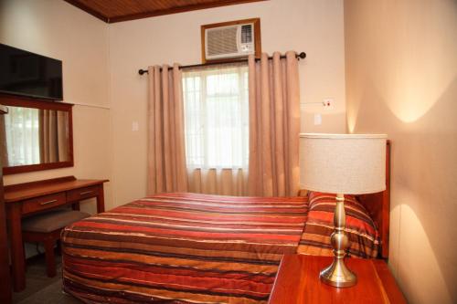 a bedroom with a bed and a desk and a window at Blyde Canyon, A Forever Resort in Matibidi
