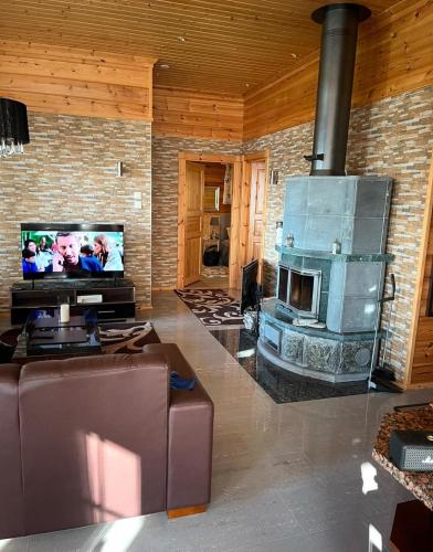 a living room with a fireplace and a flat screen tv at Villa Iltaranta - Cottage on the shore of Lake Saimaaa in Savonlinna