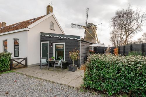 オーストカペッレにあるHello Zeeland - Vakantiewoning Noordweg 4aの風車とパティオ付きの家