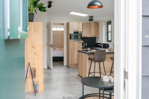 オーストカペッレにあるHello Zeeland - Vakantiewoning Noordweg 4aの木製のキャビネットとテーブルと椅子を備えたキッチン