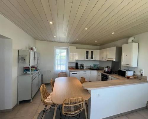 une grande cuisine avec une table et des chaises en bois dans l'établissement Maison familiale accueillante à Saint-Michel-en-l'Herm avec jardin, à Saint-Michel-en-lʼHerm