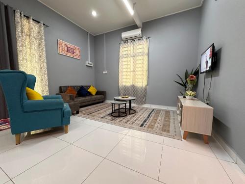 a living room with a blue chair and a tv at Tok Wan's Studio Homestay in Tanah Merah