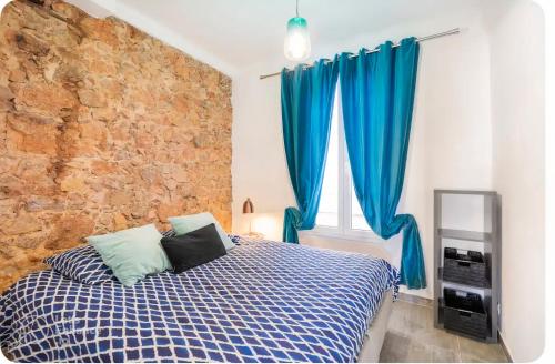 - une chambre avec un lit doté de rideaux bleus et d'un mur en pierre dans l'établissement Stay-cannes 2 bedroom Cannes beach & congress apartment, à Cannes
