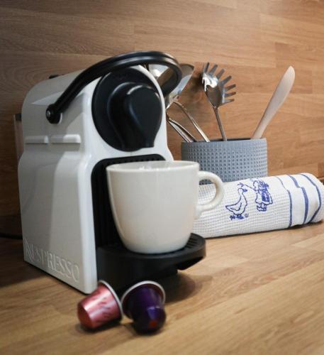 a coffee maker with a cup on a table at Esprit COTON Free parking in Huningue