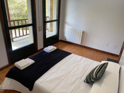 a large white bed in a room with windows at Albergue O Beque in Moaña