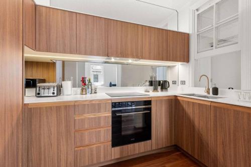 a kitchen with wooden cabinets and a black oven at Perfect Vacation Home in Dawes Point in Sydney