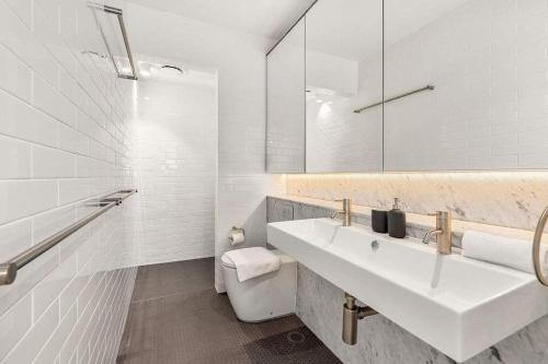 a white bathroom with a sink and a toilet at Perfect Vacation Home in Dawes Point in Sydney