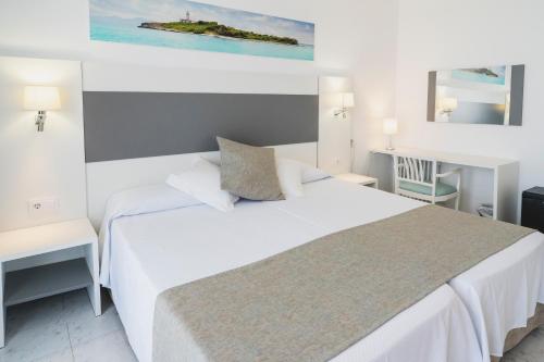 a bedroom with a white bed and two tables at Hotel Amic Miraflores in Can Pastilla