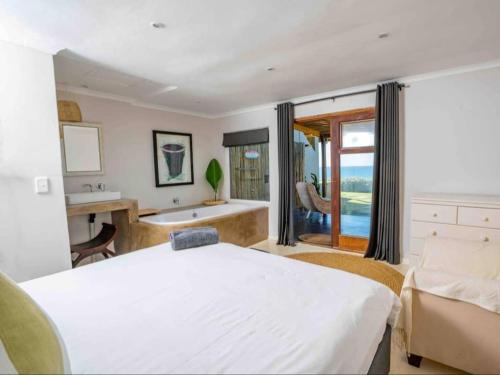 a bedroom with a bed and a tub and a sink at Highrocks Beach House in Umkomaas