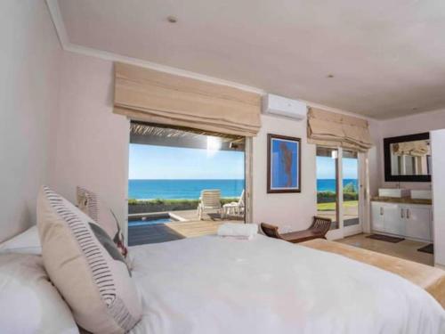 a bedroom with a large bed with a view of the ocean at Highrocks Beach House in Umkomaas