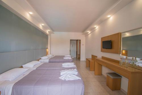 a hotel room with four beds and a television at Dennys Inn Hotel in Kalamaki