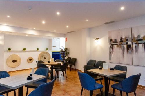 a restaurant with tables and chairs and paintings on the wall at HOTEL HACIENDA SANTA BARBARA in Castilleja de la Cuesta