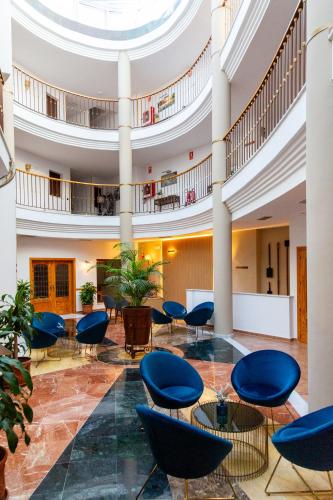a lobby with blue chairs and tables in a building at HOTEL HACIENDA SANTA BARBARA in Castilleja de la Cuesta