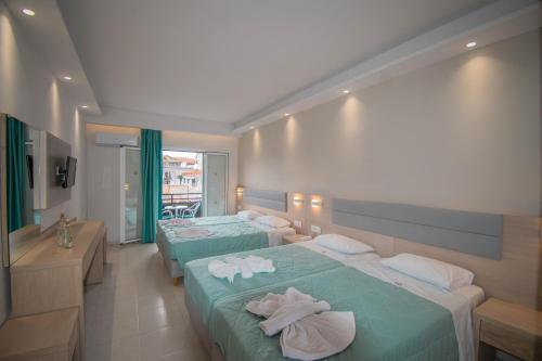 a hotel room with two beds with towels on them at Dennys Inn Hotel in Kalamaki